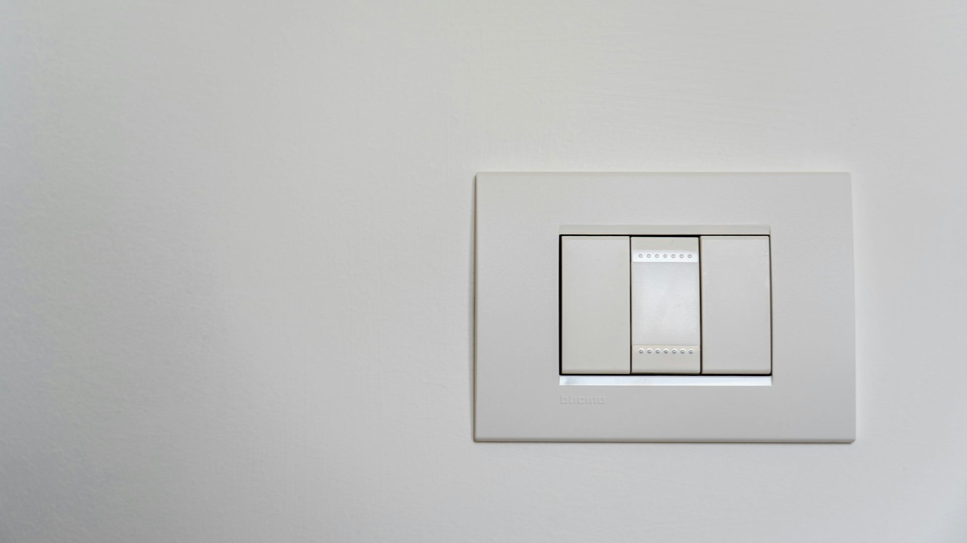White light switch on a white wall, with three toggles.
