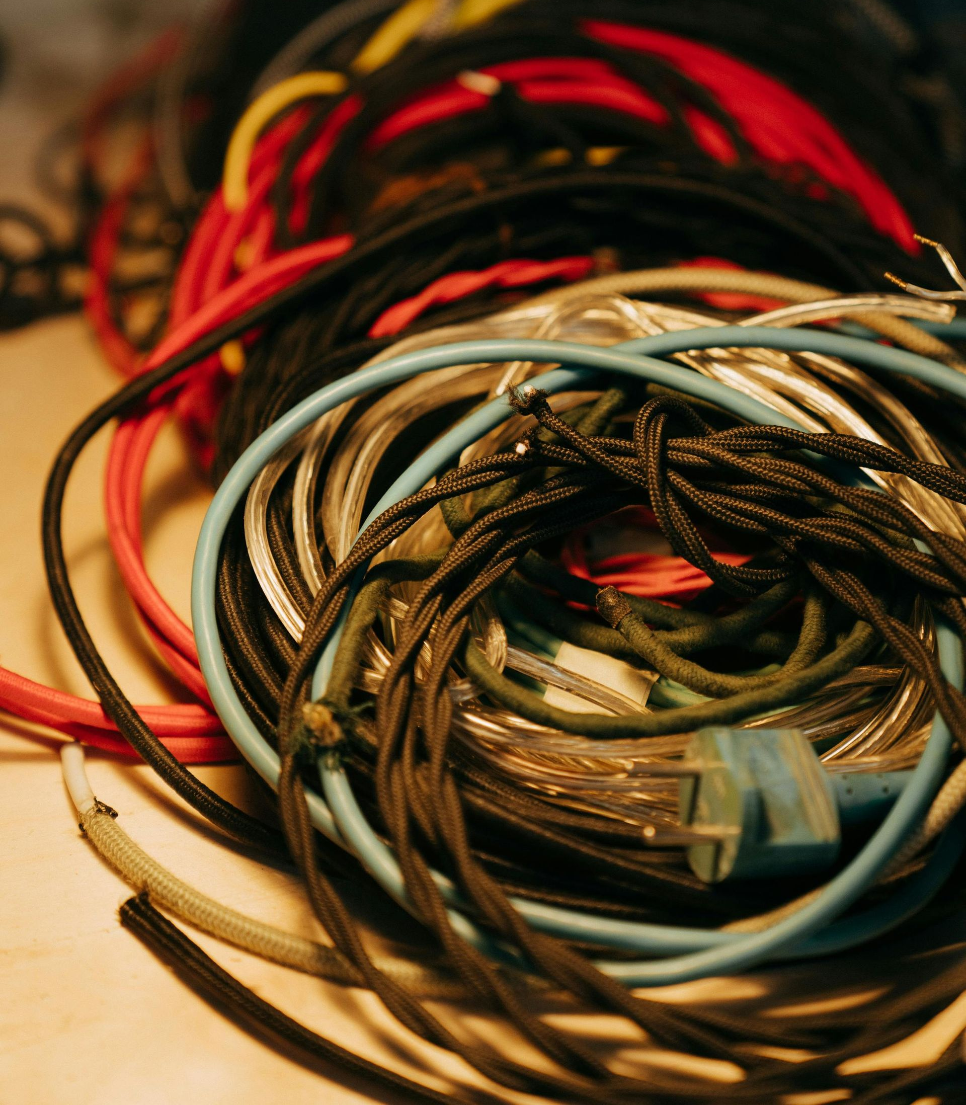 Tangled pile of colorful electrical cords: red, black, blue, and gray.