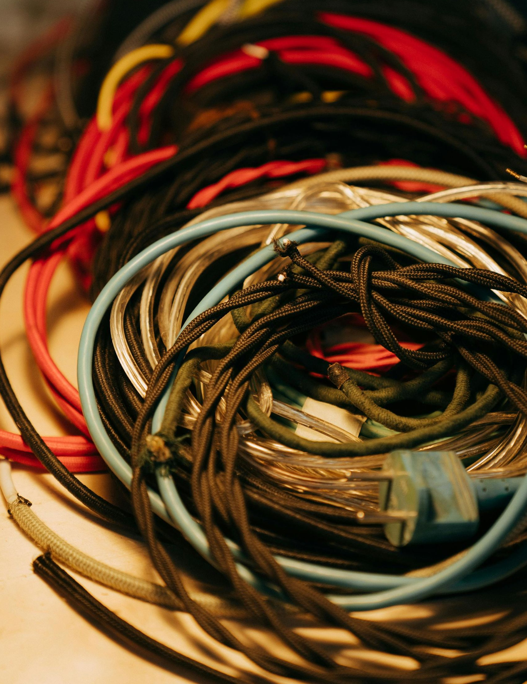 Tangled bundle of colorful electrical wires, including red, black, blue, and yellow cords.