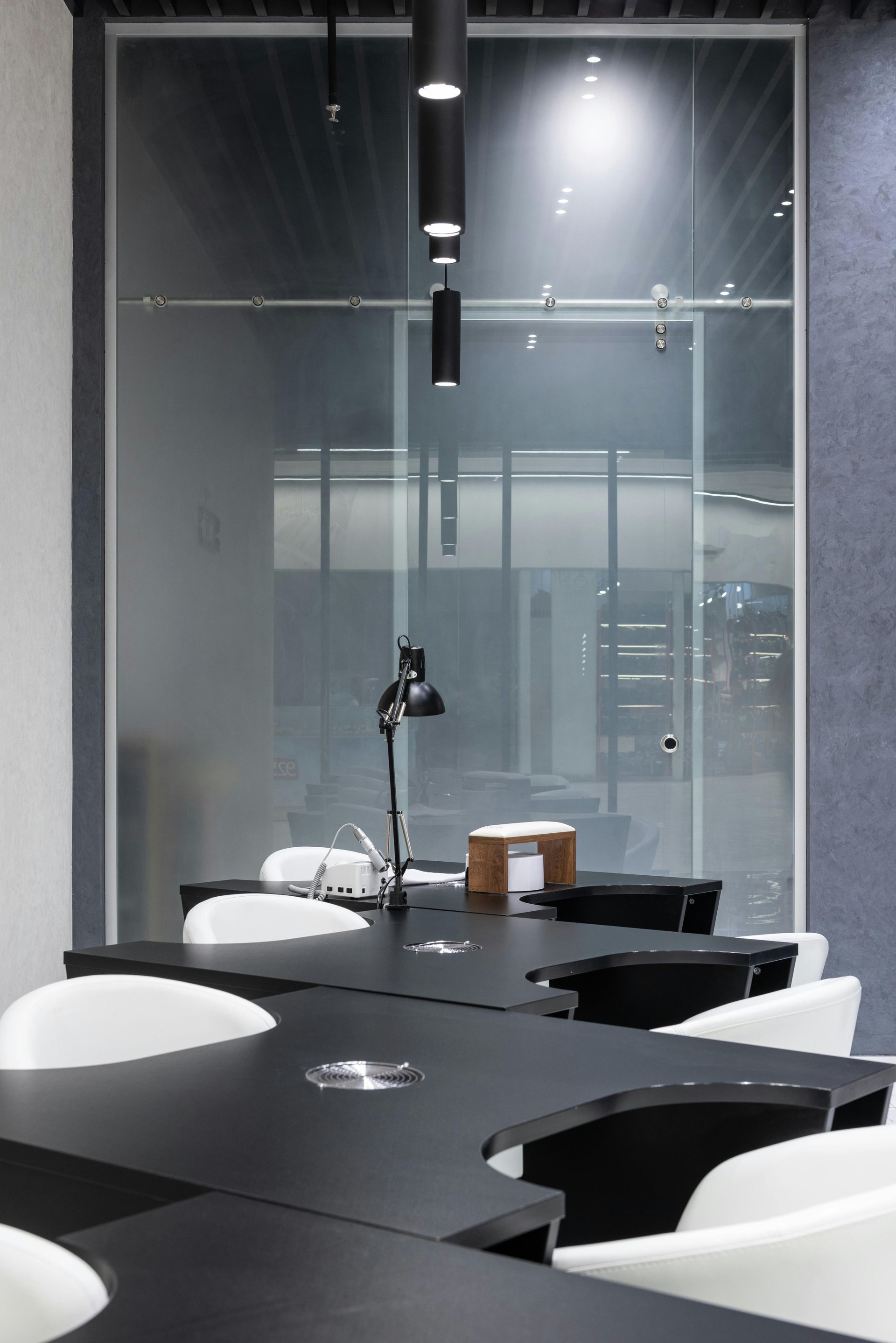 Conference room with black tables, white chairs, and glass wall. Modern office setting.