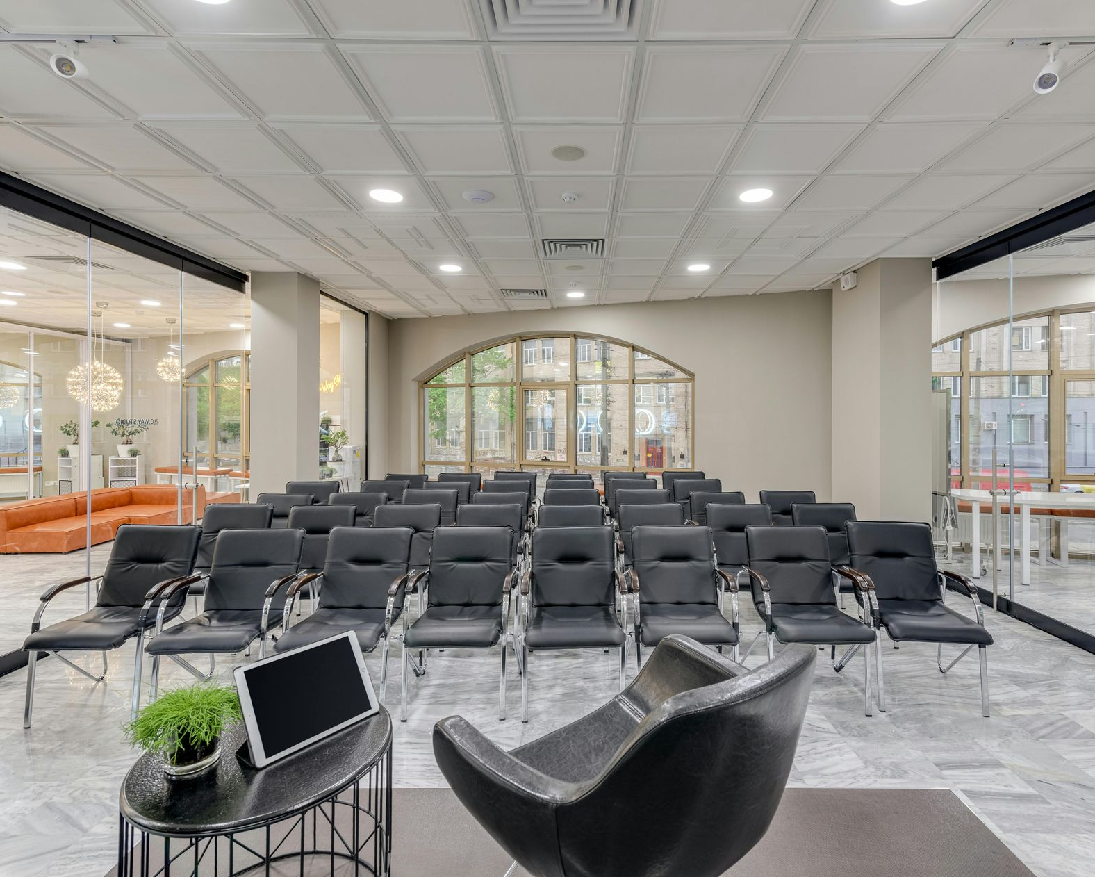 Conference room with rows of chairs, a speaker's chair, and a table with a laptop.