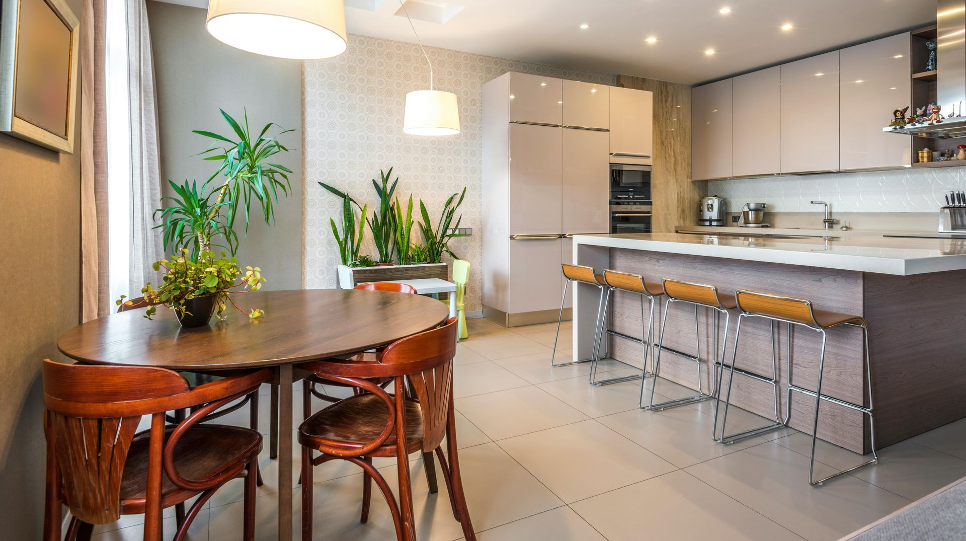 Modern kitchen with dining area, featuring a table, chairs, island, and overhead lighting.