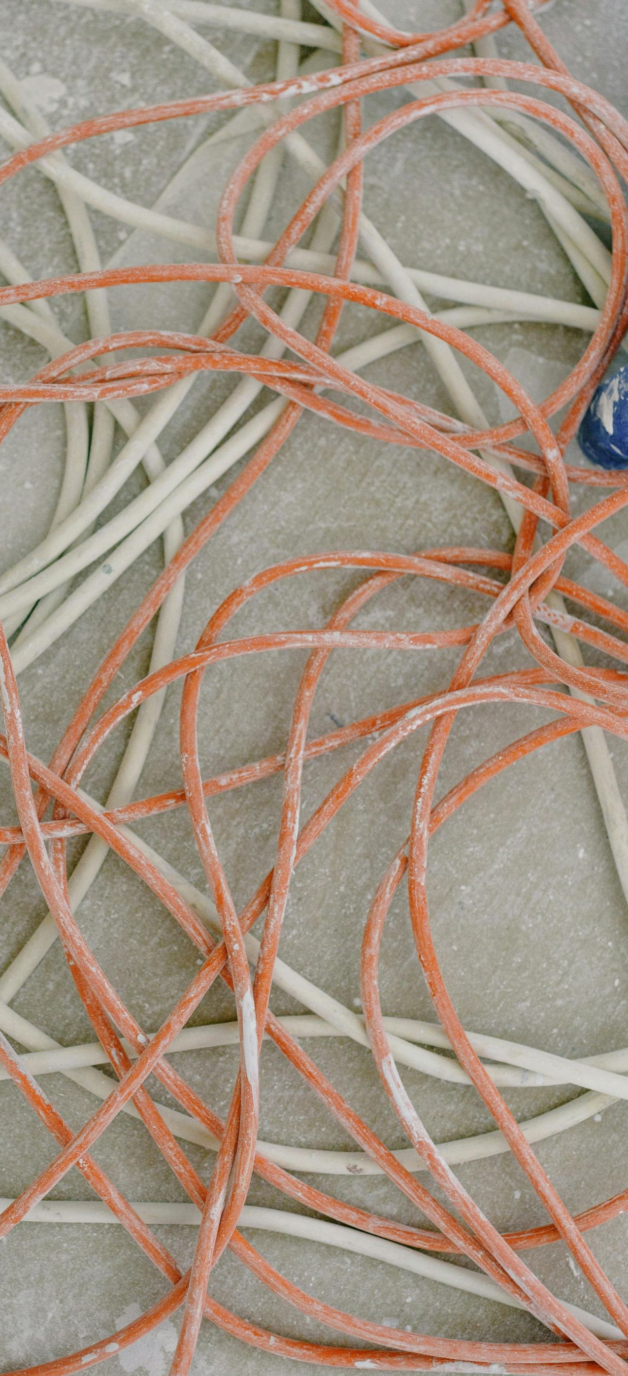 Tangled strands of orange and white pasta on a textured surface.