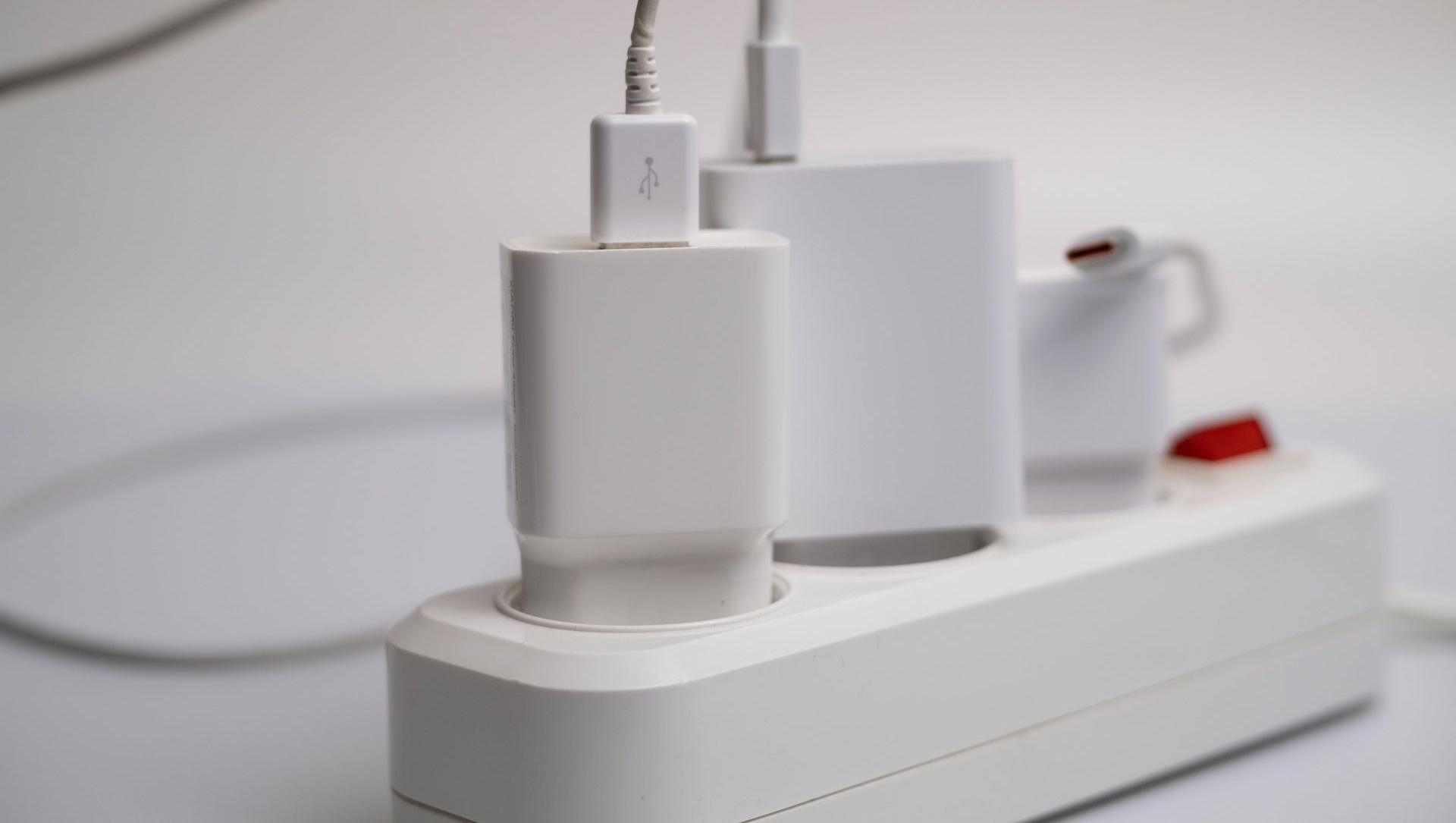 White charging bricks plugged into a white power strip.