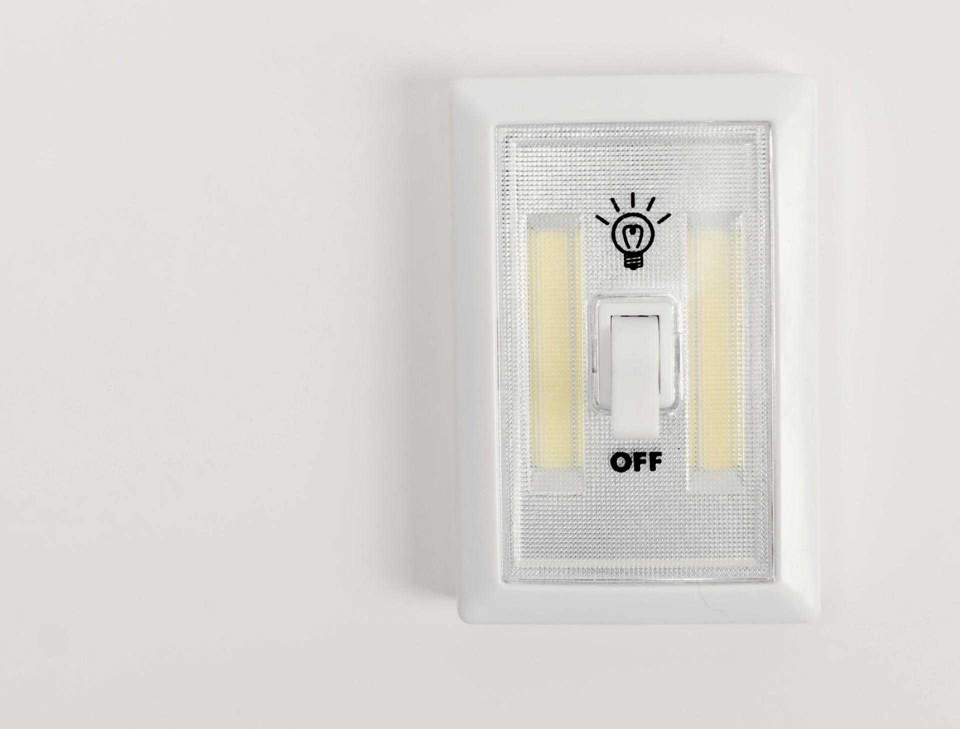 White wall with a small, rectangular, white light switch in the