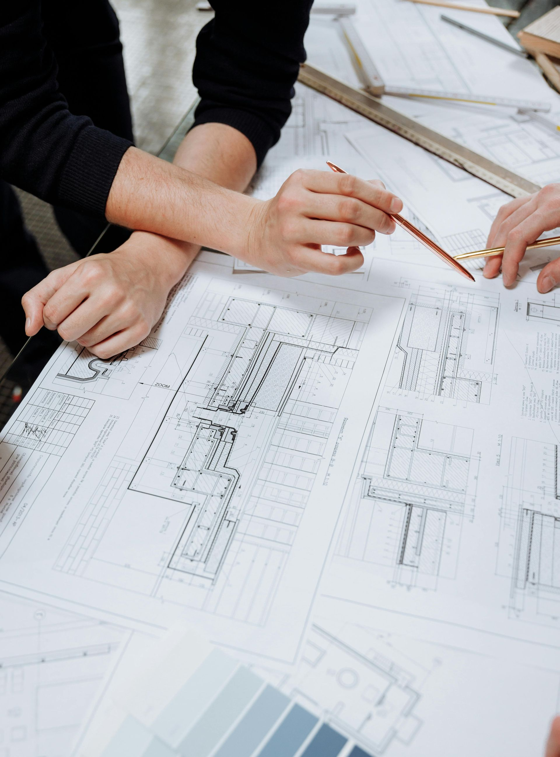 Hands pointing to architectural blueprints on a table, discussing design details.