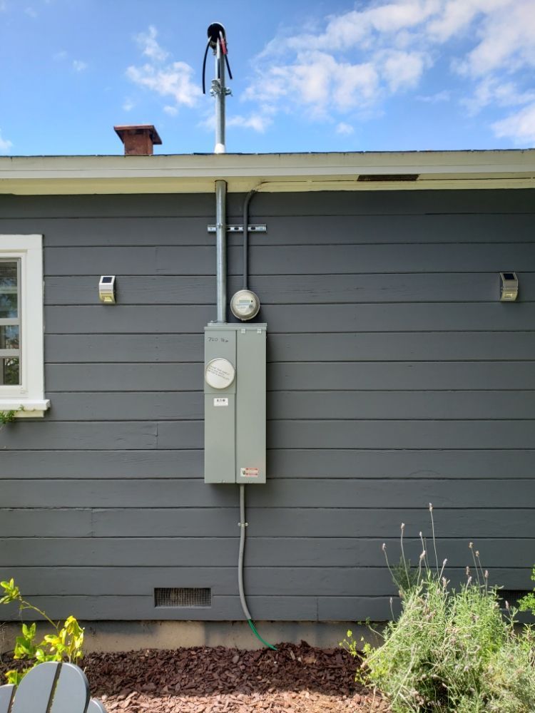 A gray house with a electrical box on the side of it.
