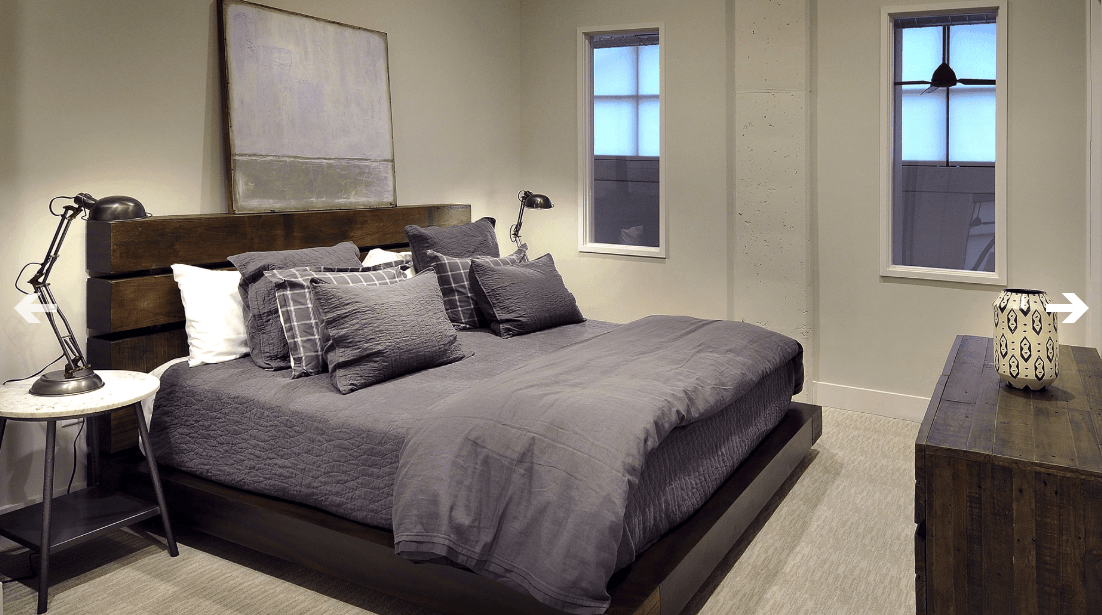 A bedroom with a large bed and two windows