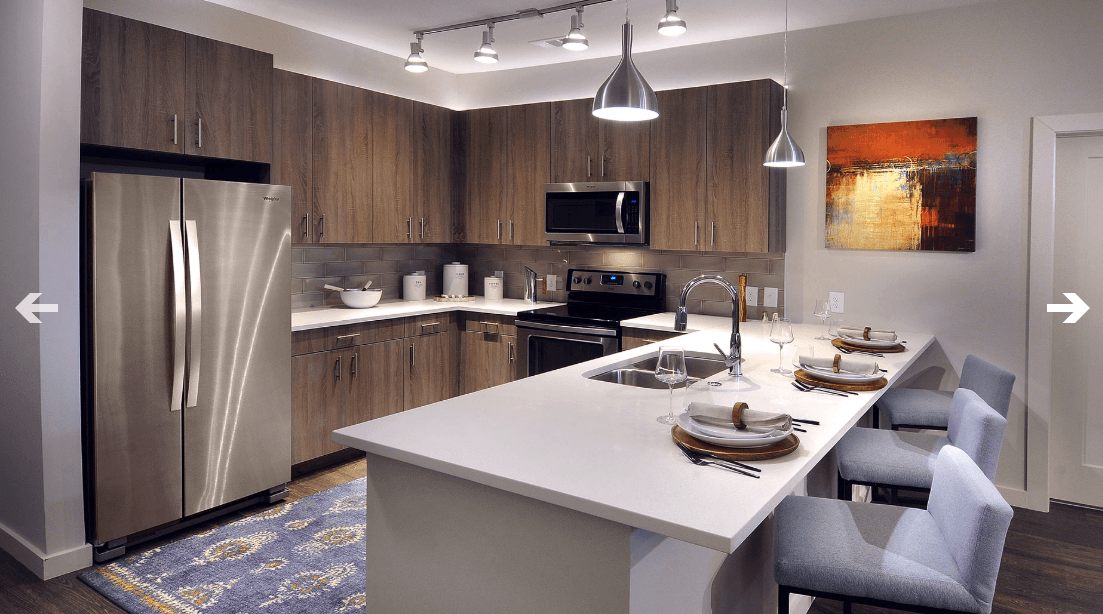A kitchen with stainless steel appliances , wooden cabinets and a large island.