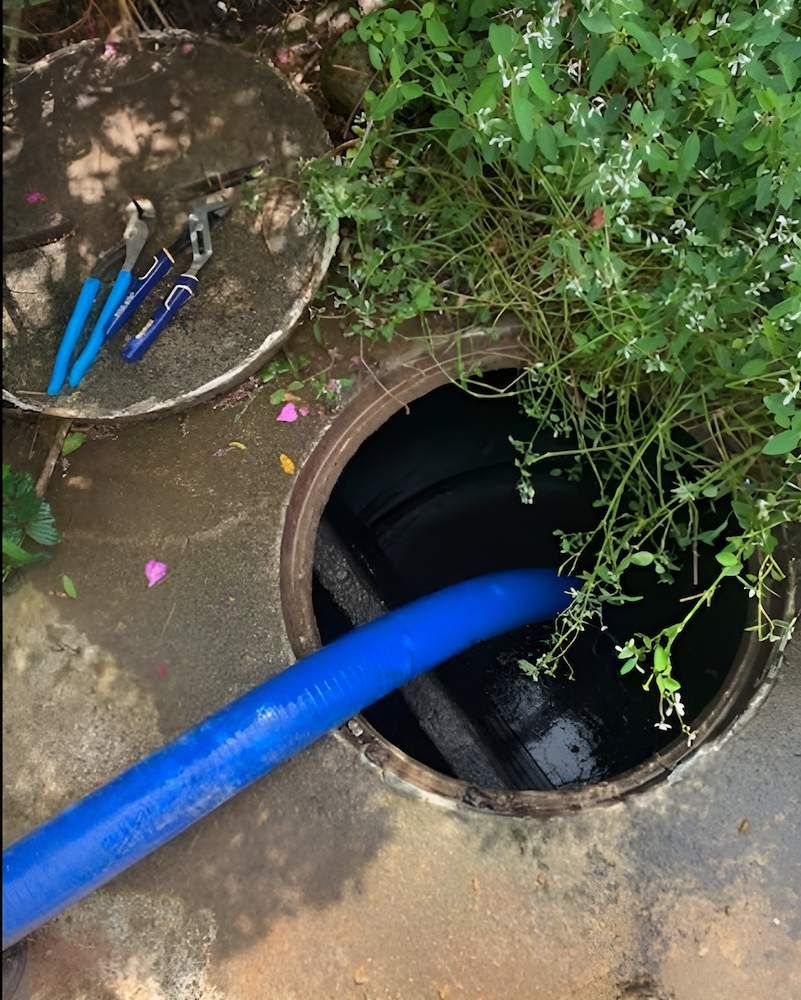 A Blue Hose is Coming Out of a Manhole Cover — Glenview Septic & Liquid Waste Removal In Maleny, QLD