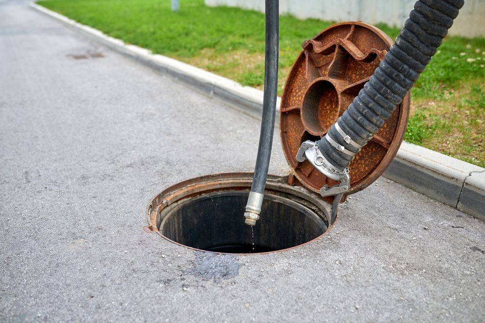 A Manhole Cover is Open and a Hose is Coming Out of It — Glenview Septic & Liquid Waste Removal In Caboolture, QLD