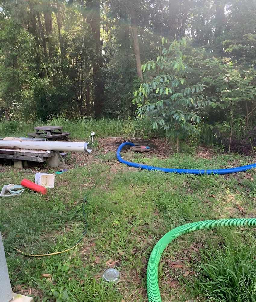 A Green Hose is Laying in the Grass Next to a Blue Hose — Glenview Septic & Liquid Waste Removal In Maleny, QLD