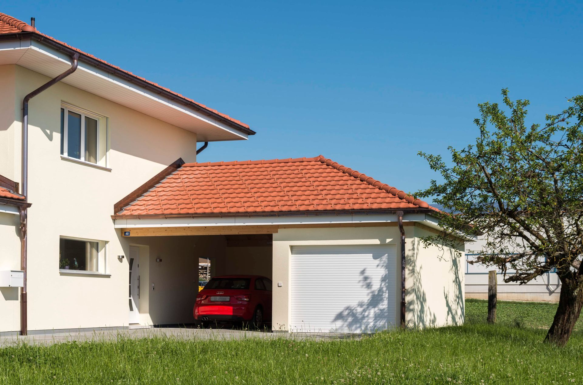 Ein rotes Auto steht in einer Garage neben einem Haus.