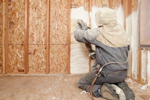 Worker Spraying Foam Insulation on Wall Panels in Chicagoland Home