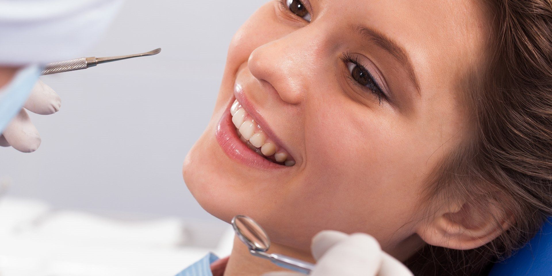 girl in dental chair smiling showing off her tooth for cracked tooth repair