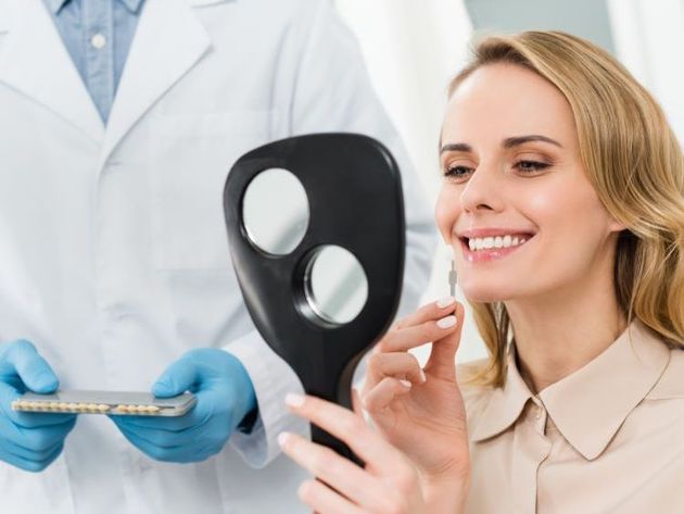 lady looking in a handheld mirror smiling for general dentistry