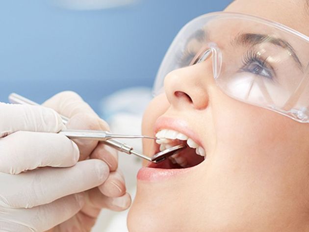closeup of a face of a person wearing eye protection while getting their teeth examined for cosmetic dentistry