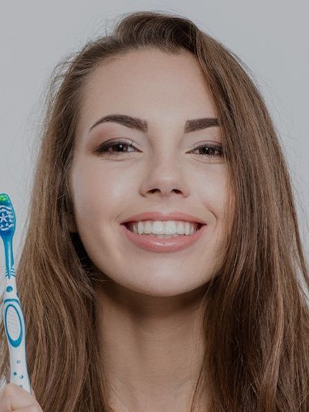 girl smiling holding tooth brush for cleanings and exams