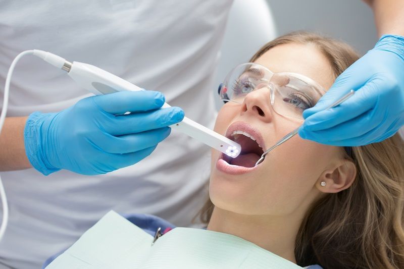 girl smiling with the dentist examining her teeth for full mouth reconstruction