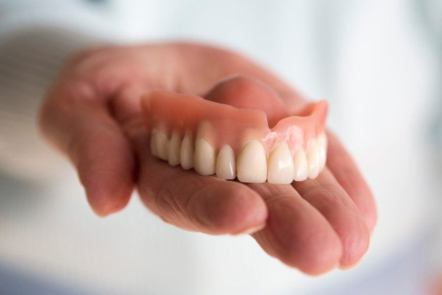 Woman Holding Denture — Eastpointe, MI — Eastland & Professional Dental Center