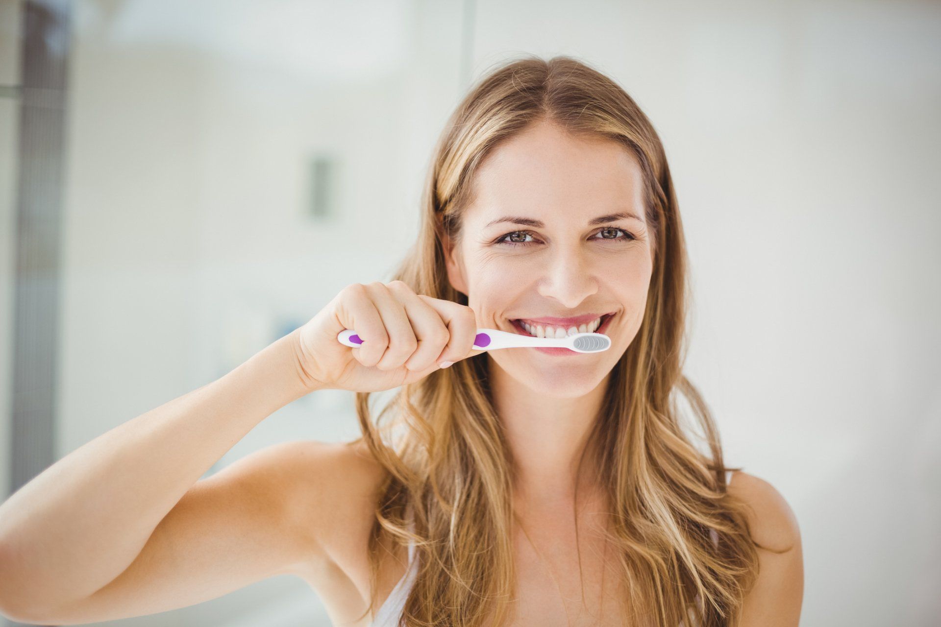 Woman Cleaning Teeth at Bathroom — Eastpointe, MI — Eastland & Professional Dental Center