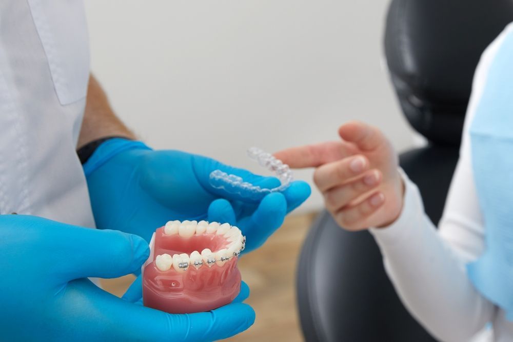 A Dentist is Holding a Model of a Person 's Teeth With Braces — Coronation House Dentist in Nambour, QLD