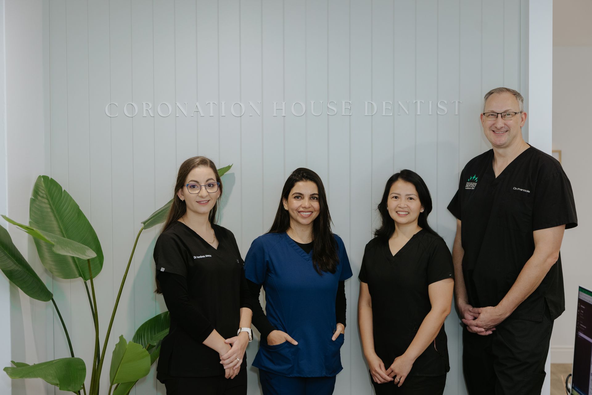Four dental staff in scrubs pose in front of a wall — Coronation House Dentist in Nambour, QLD