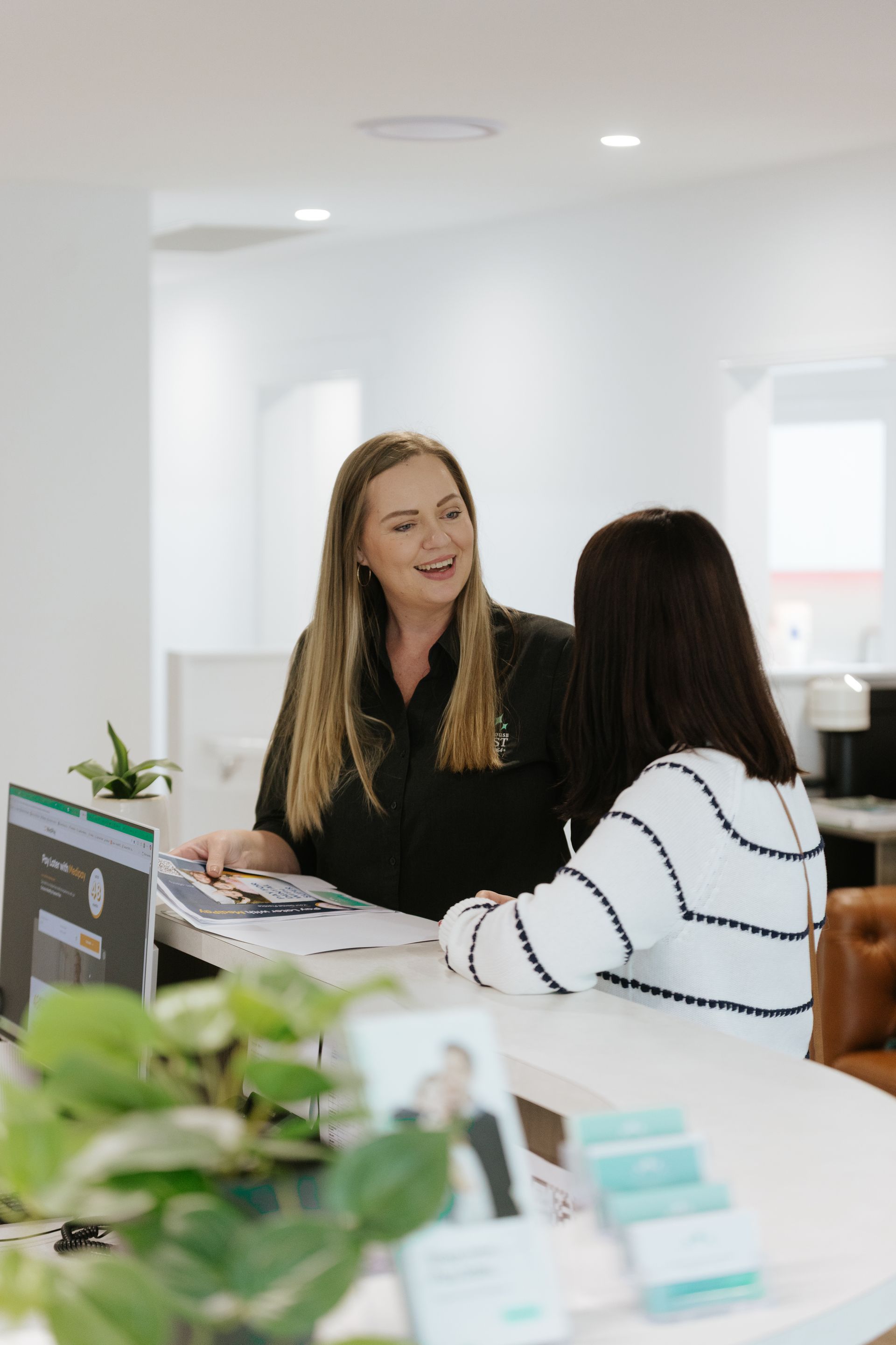 A Woman is Sitting in a Dental Chair While a Dentist Holds a Model of Her Teeth — Coronation House Dentist in Nambour, QLD