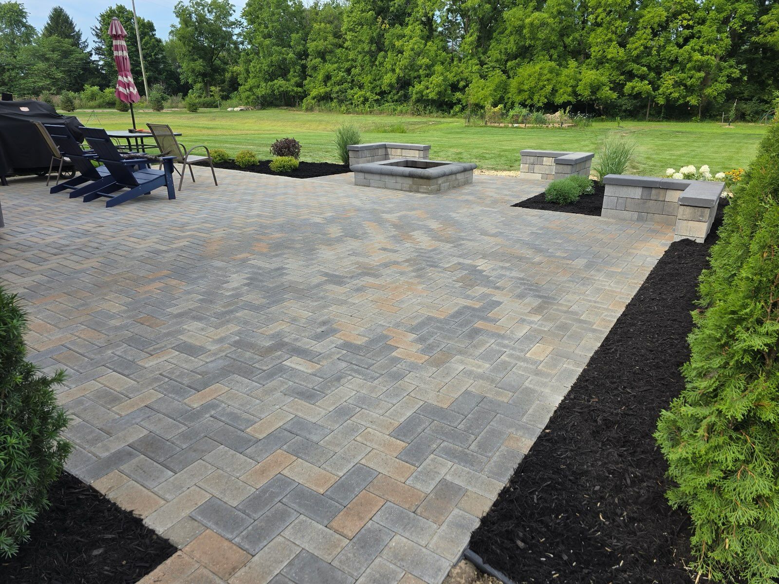 A sunken stone fire pit patio with built-in stairs, ambient lighting, and outdoor seating in a landscaped backyard.