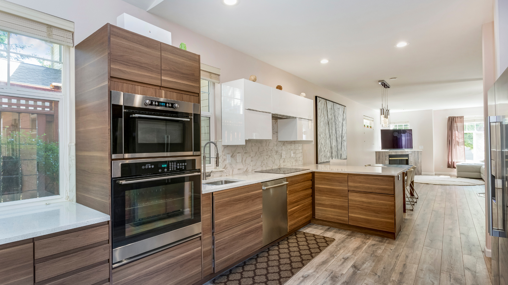 Modern kitchen with wood cabinetry, stainless appliances, white cabinets, and a long island under recessed lights