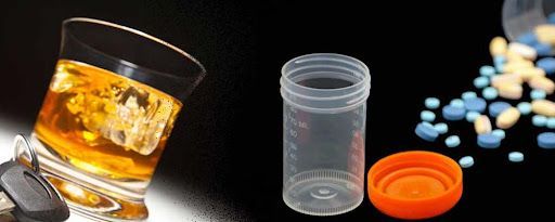 A glass of whiskey next to a bottle of pills.