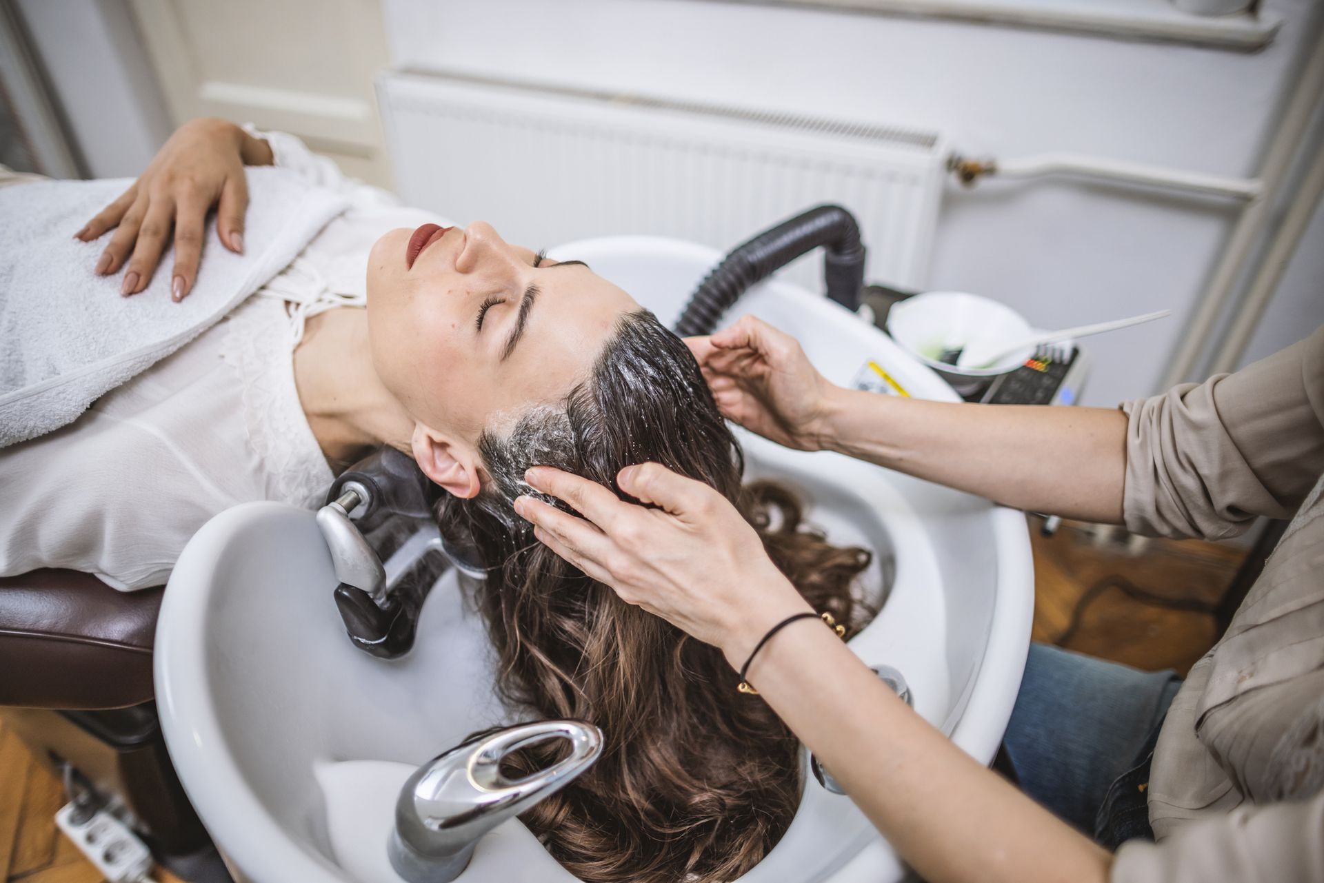 Una donna si sta lavando i capelli nel lavandino di un salone.