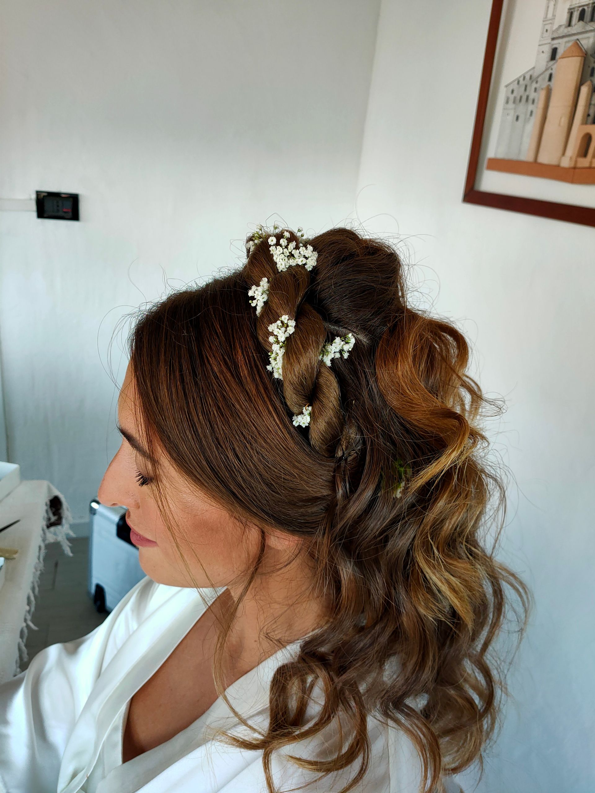 Una donna indossa uno chignon intrecciato con fiori tra i capelli.