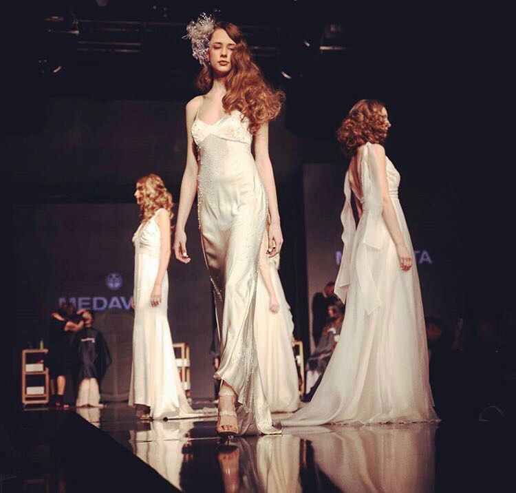 Una donna in abito bianco cammina su una passerella