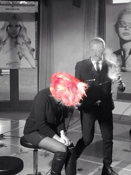 Un uomo che asciuga i capelli rosa di una donna in un salone