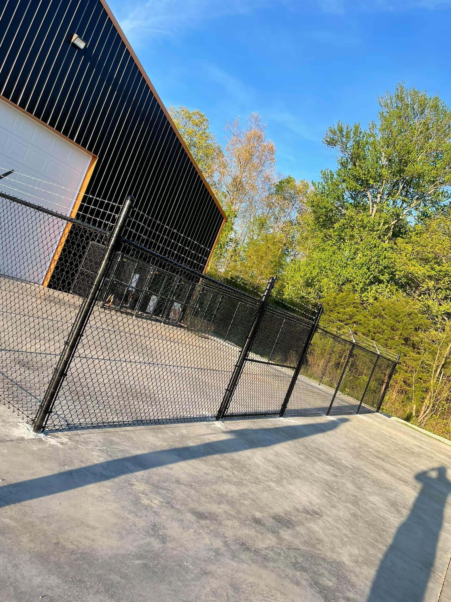 A chain link fence is surrounding a building with trees in the background.