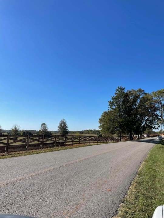 A road with a wooden fence on the side of it.