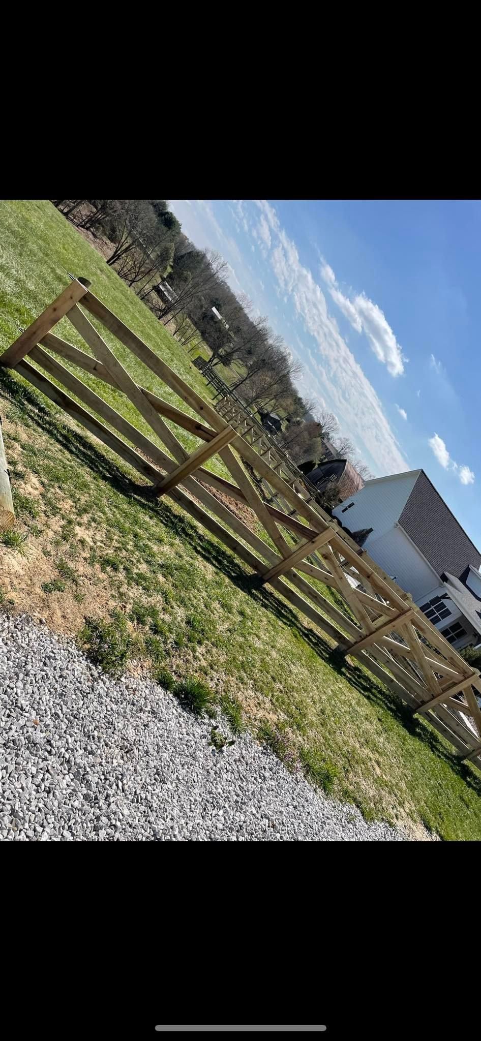 A wooden fence is sitting in the middle of a grassy field.