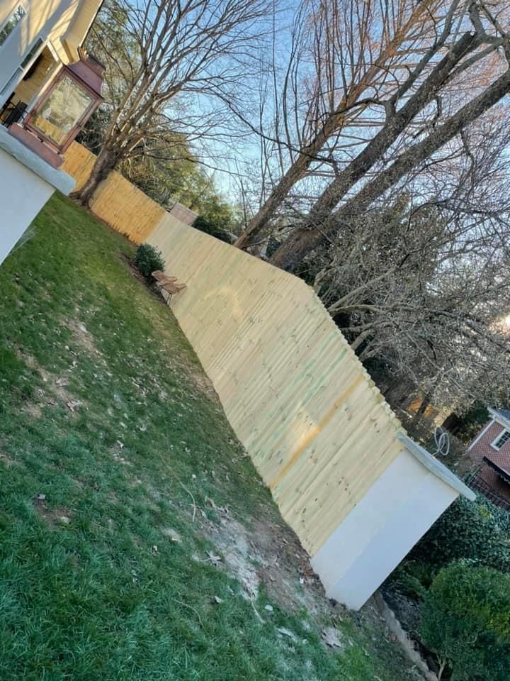 A wooden fence is being built in the backyard of a house.