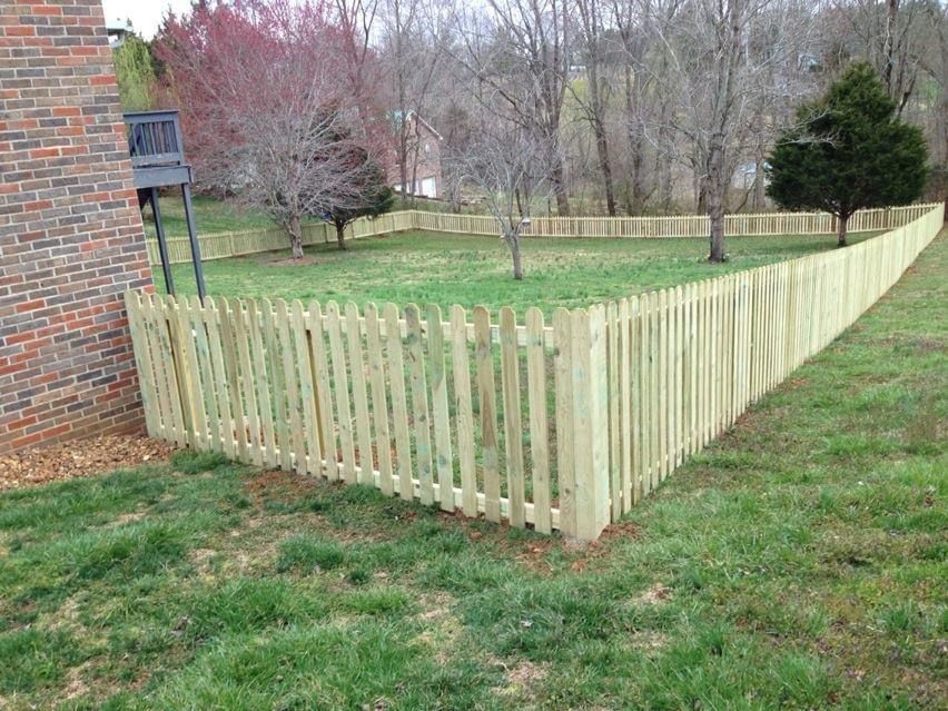 A wooden picket fence surrounds a lush green yard.