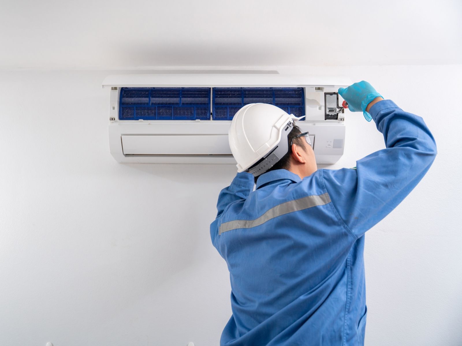 A man is working on an air conditioner in a room.