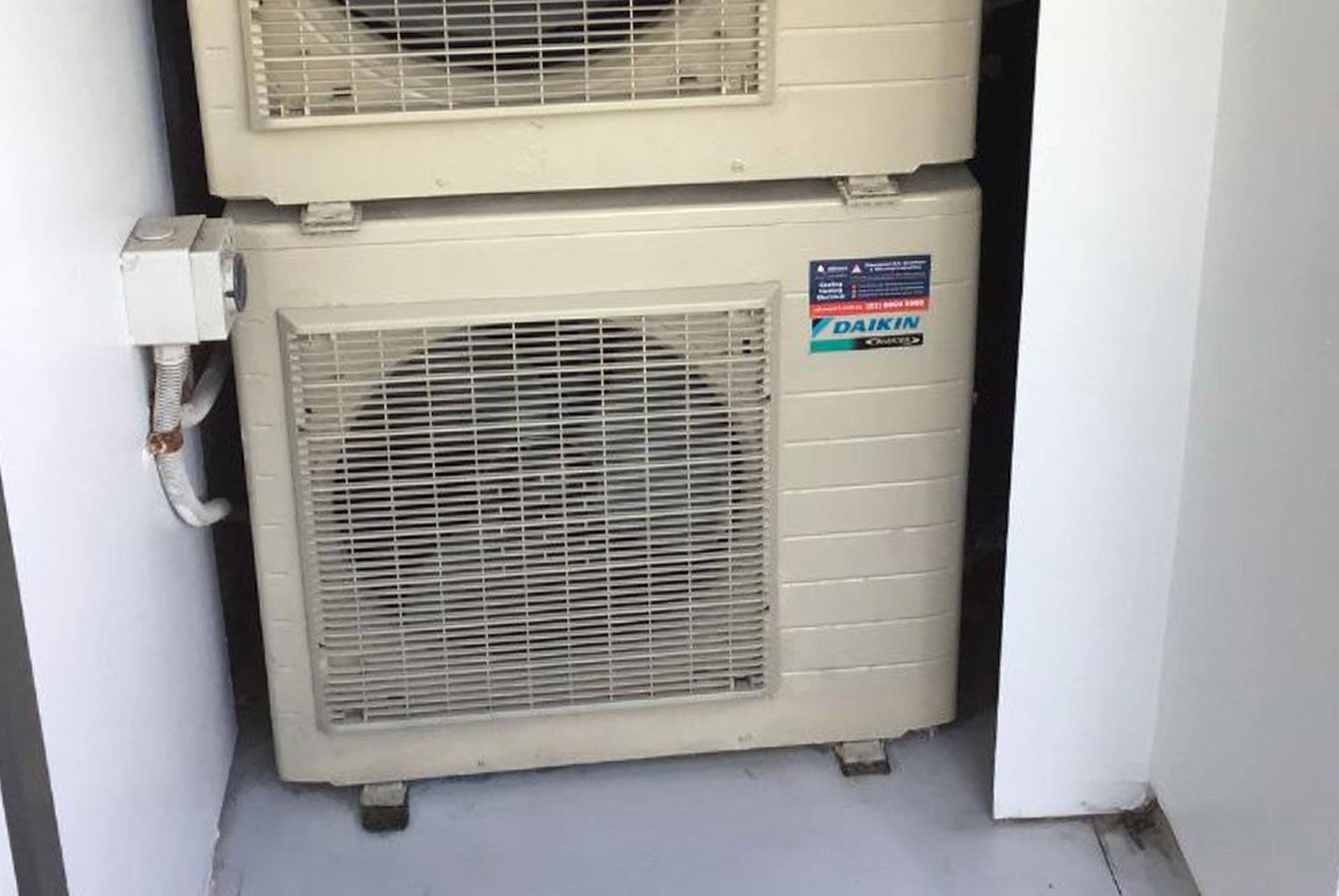 Two air conditioners are stacked on top of each other in a room.