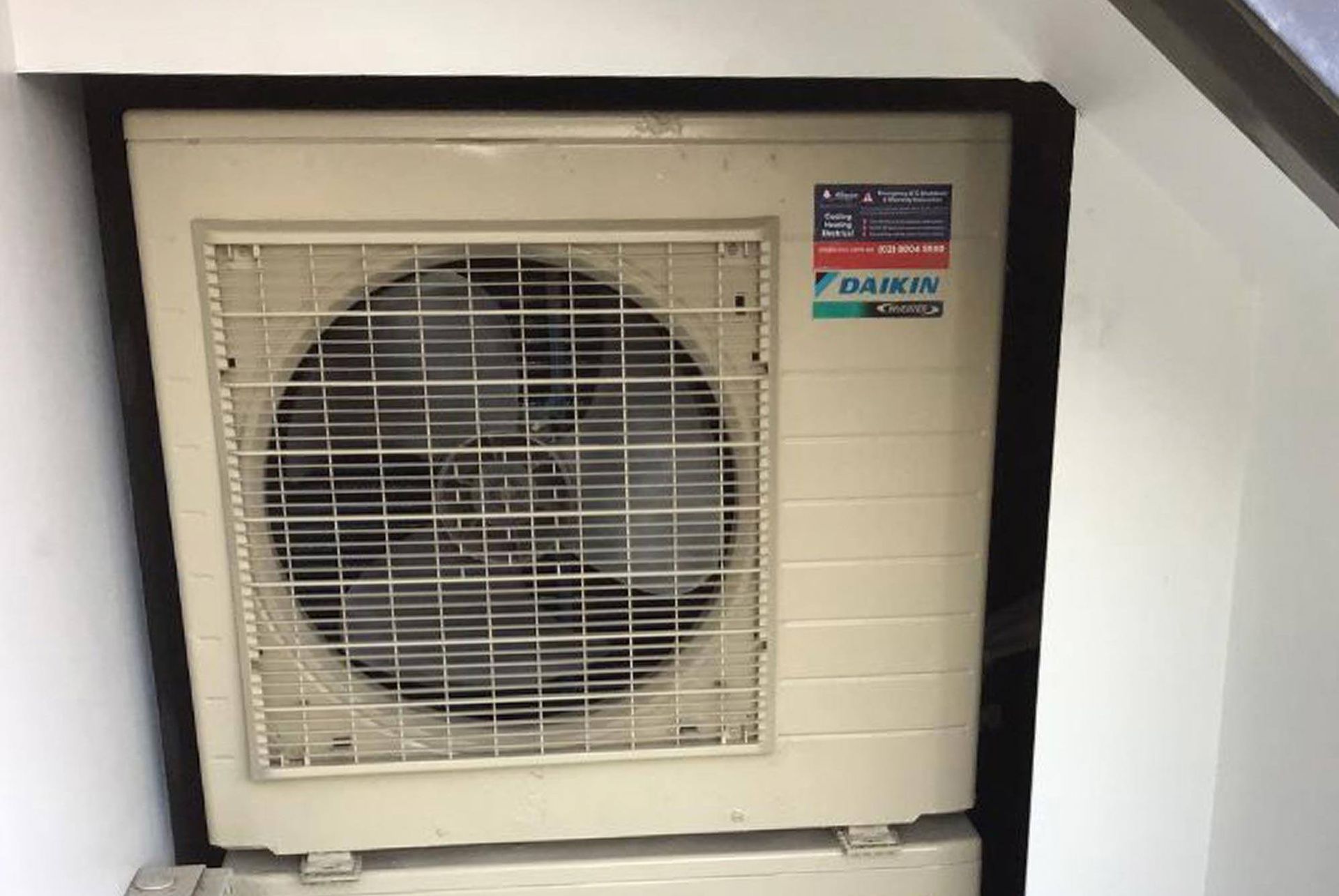 A daikin air conditioner is sitting in a corner of a room