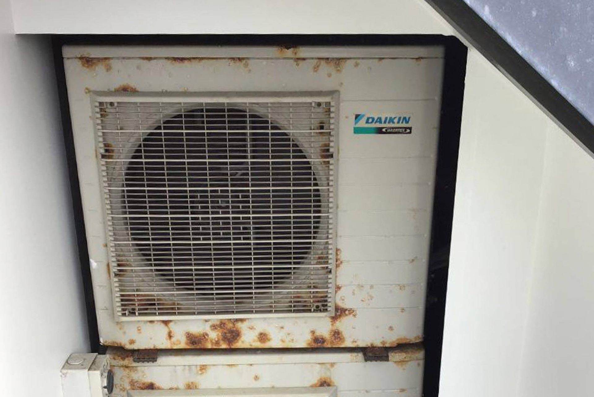 A white daikin air conditioner is sitting on a white wall