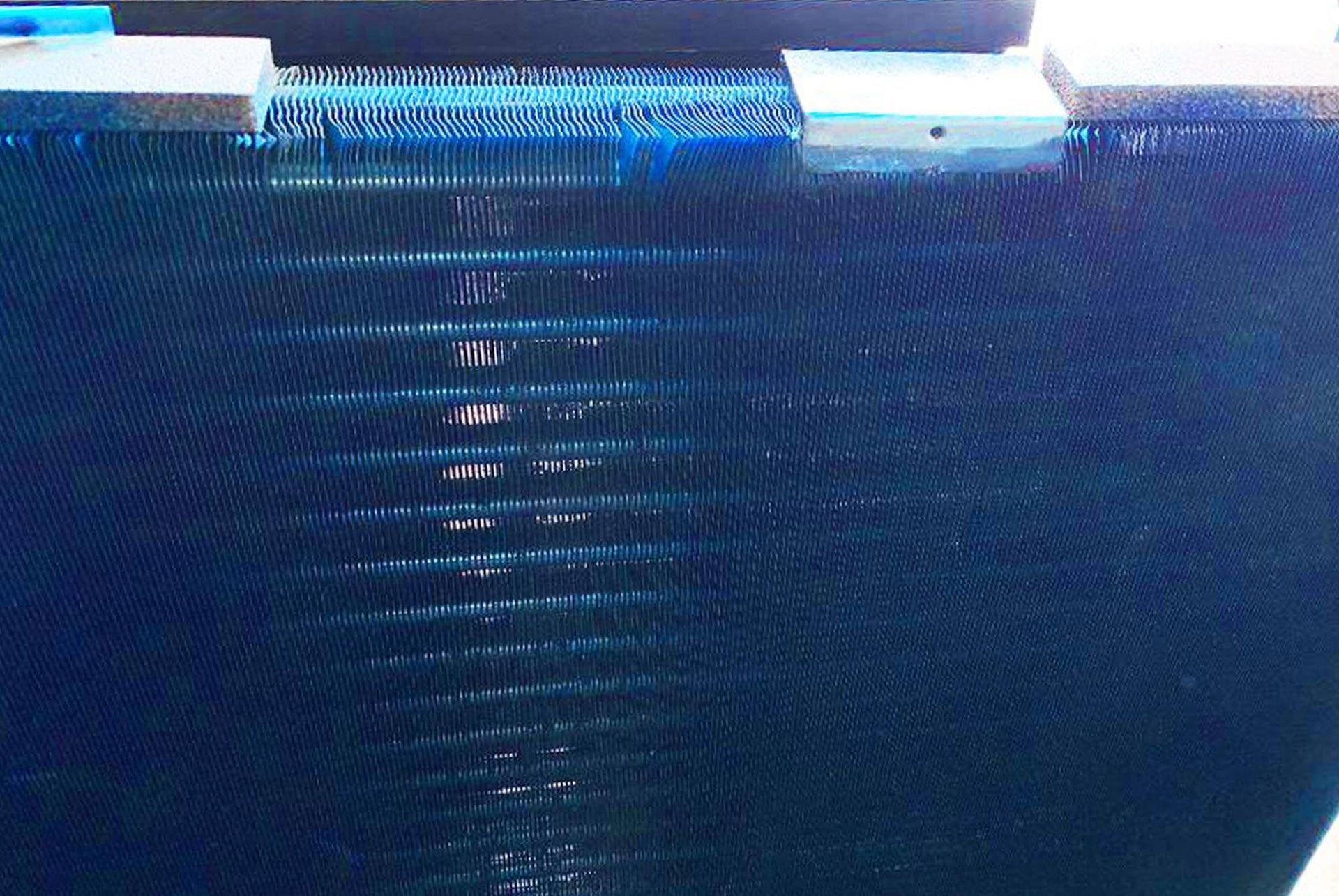 A blue swimming pool with a reflection of a building in the water