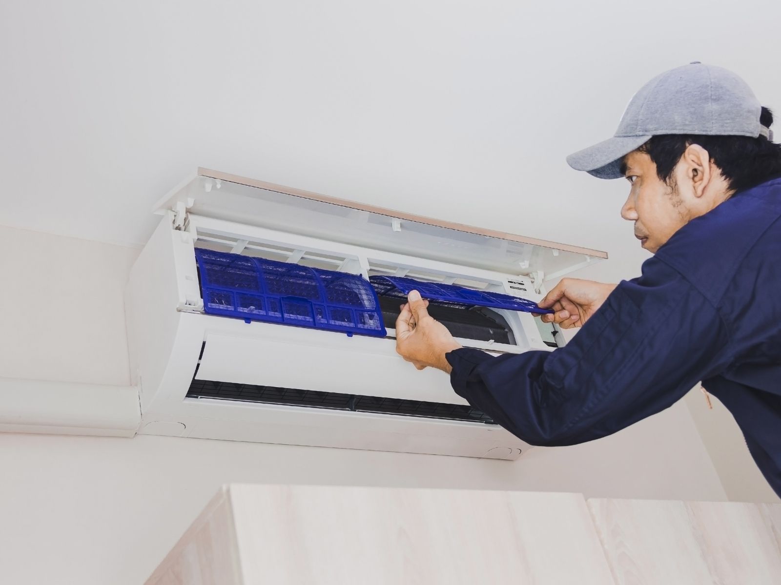 A man is cleaning an air conditioner with a brush.