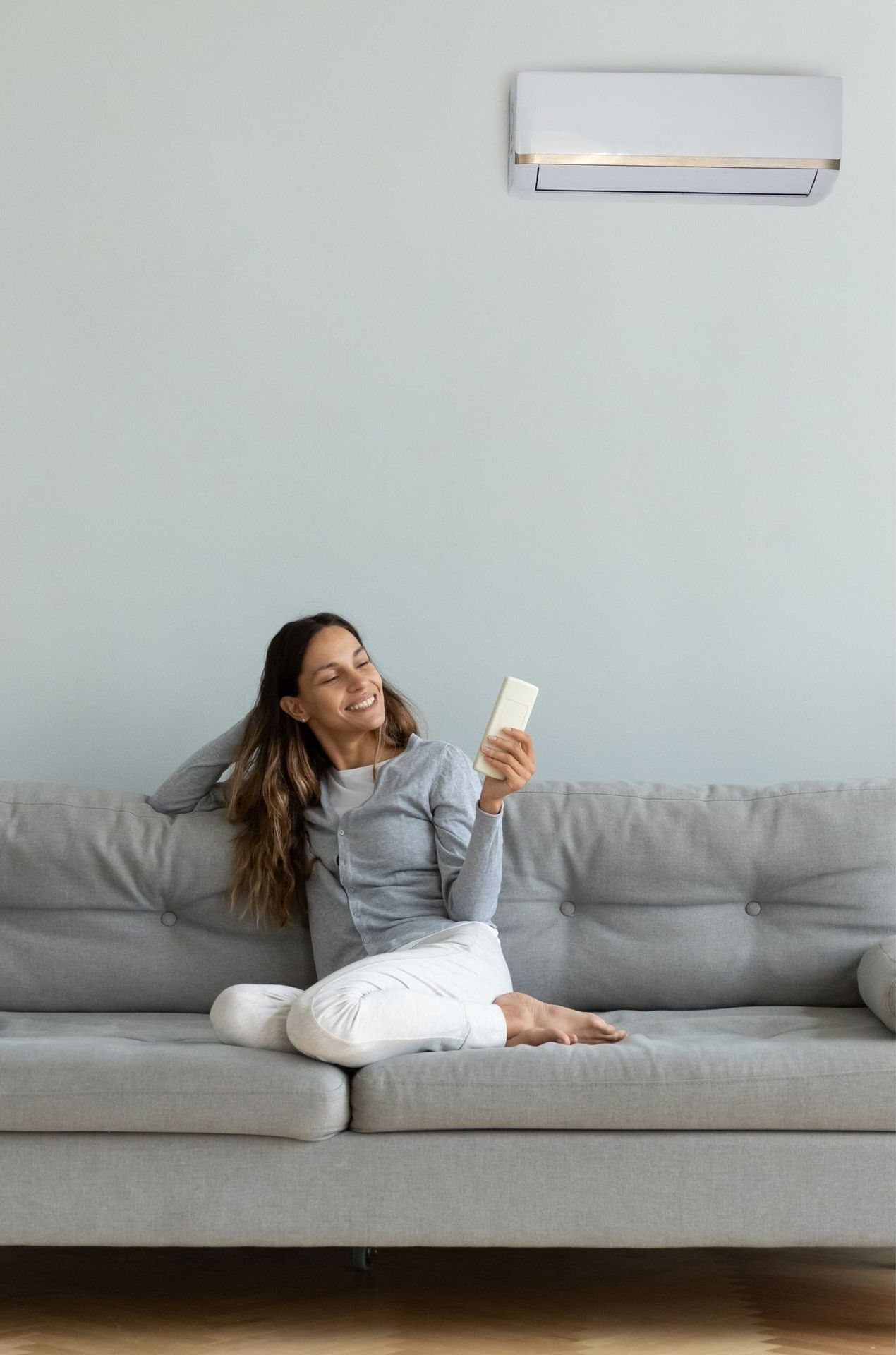 A woman is sitting on a couch holding a remote control.