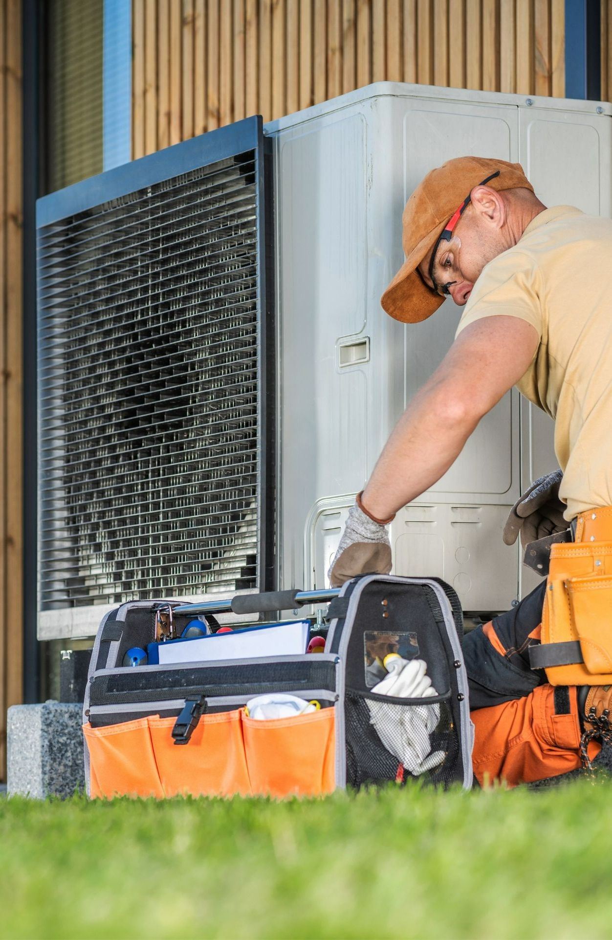 A man is working on an air conditioner outside of a building.