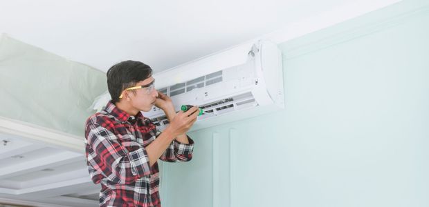 A man is installing an air conditioner on the wall.