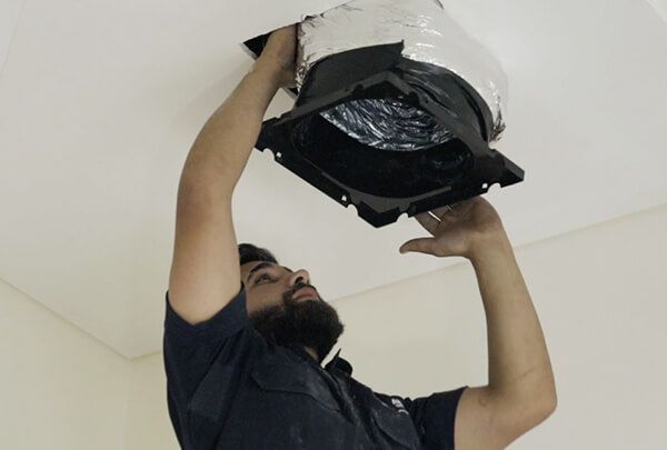 A man is fixing a fan on the ceiling.